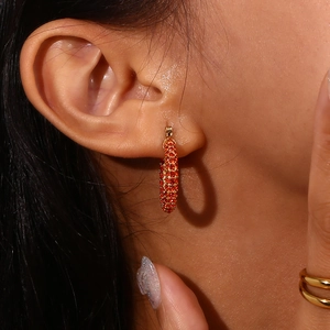 Close-up of 18K gold-plated hoop earring with vibrant orange cubic zirconia crystals