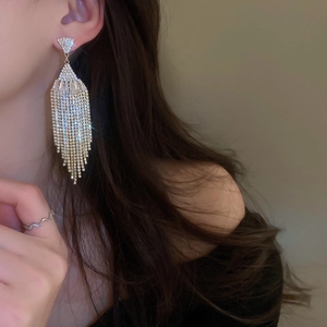 Close-up of sparkling tassel earrings with zirconia inlay on a female model