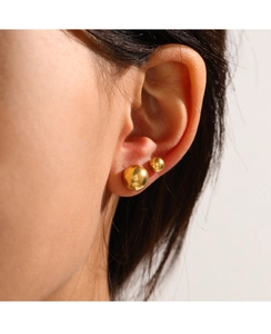 Close-up of gold ball earrings on ear showcasing polished stainless steel texture