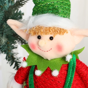 Cute Christmas elf doll ornament with red and green sequins on a blurred tree background