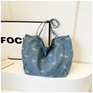 Detailed macro view showing the textured denim fabric and white bow patterns on the tote bag