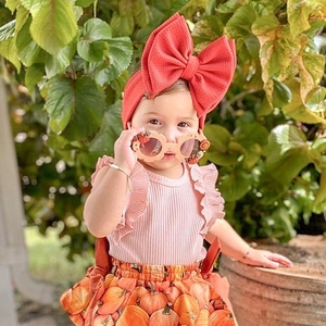 Detail of baby girl Halloween set with pumpkin skirt, pink top, and red bow headband
