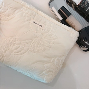 Detail of white quilted floral embroidery pouch with a simple wish woven label tag