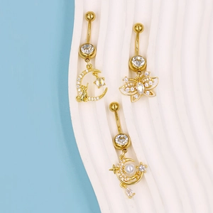 Makroaufnahme goldener Bauchnabelpiercings mit Mond-Katze, Zirkon-Schmetterling und Sternenperlen