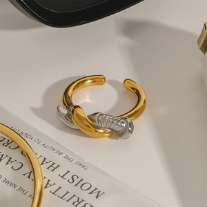 Bague ouverte torsadée minimaliste en finition or et argent sur fond blanc