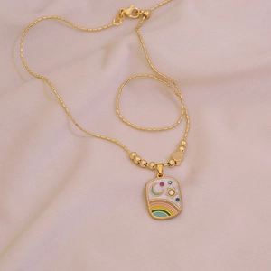 Golden stainless steel necklace with enamel star and moon square pendant on beige fabric