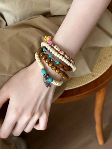 Détail de bracelets de perles de bois bohèmes avec pendentifs plume et tournesol
