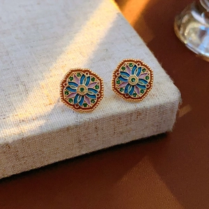 Macro shot of octagonal enamel earrings with colorful floral patterns and gold accents