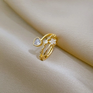 Detail shot of heart and star gold-plated ring with sparkling cubic zirconia on silk