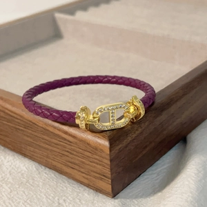 Dettaglio del braccialetto in pelle intrecciata viola con chiusura a diamante dorata su vassoio