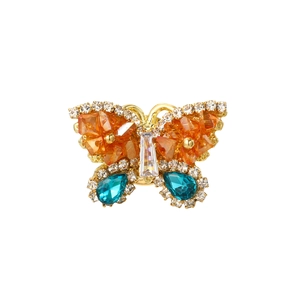 Detail of golden butterfly brooch with orange and teal crystals and pavé rhinestones