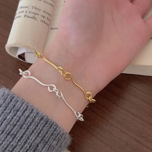 Close-up of minimalist gold and silver wavy link bracelets on a vintage book