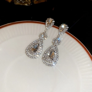Macro view of silver droplet tassel earrings with shimmering crystals on white plate