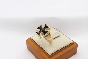 Close-up of gold men's cross ring with black enamel inlay on a wooden display stand