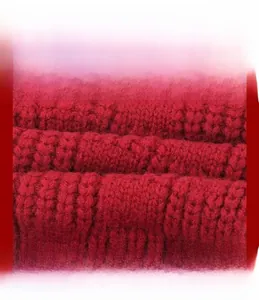 Macro detail of red knitted scarf showing soft cable knit texture and high-quality wool fabric