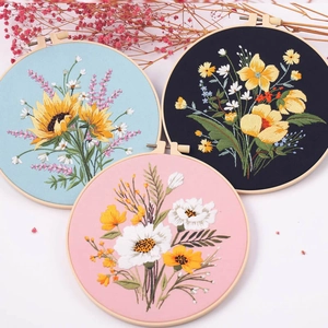 DIY hand embroidery kit with floral patterns on blue, black and pink fabric in wood hoops