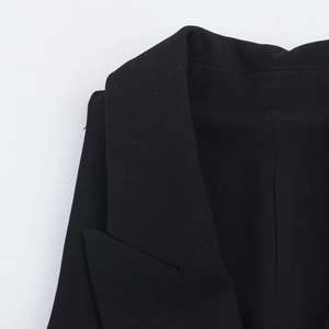 Gros plan du col de la veste noire montrant la texture raffinée du tissu et les coutures