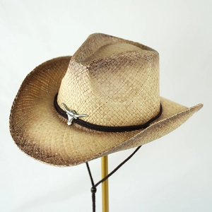 Detail of western straw cowboy hat featuring a silver bull head metal ornament and braided band