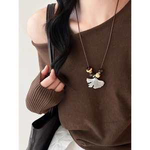 Close-up of model wearing silver ginkgo leaf pendant on brown cord with beads