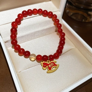 Elegante bracciale di perline in agata rossa con ciondolo a cavallo dorato in un portagioie