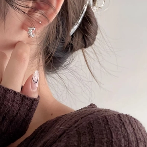 Close-up of irregular liquid metal style 925 silver stud earring worn on model ear