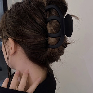 Close-up of large black matte claw clip with hollow circular design on hair