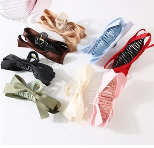 Flat lay of satin bow hair claws in eight elegant colors including champagne and blue