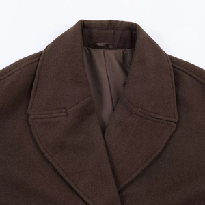 Detailed close-up of dark brown wool coat lapel showcasing premium texture and stitching