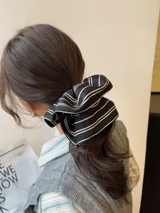 Detail of a large black striped scrunchie with bow tie design worn on a ponytail