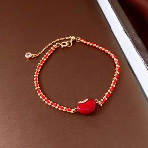Makro-Detail des roten Kordelarmbands mit Goldperlen und kristallbesetztem Anhänger