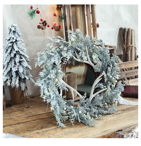 Detail of Christmas wreath with white antlers, frosted pine needles, and pine cones