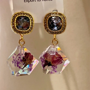 Detail of 18K gold plated vintage earrings featuring dried flowers in resin charms