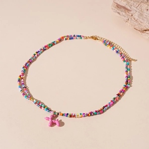 Détail d'un collier à deux couches de perles colorées avec pendentif chien ballon rose