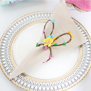 Close-up of a bunny ear napkin ring with pine needles and berries on a linen napkin
