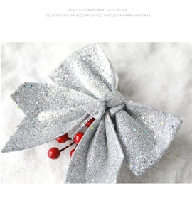 Close-up of a silver sequined Christmas bow with red berries on a snowy white background