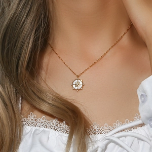 Collana a bussola dorata con inserto in conchiglia bianca sul collo della modella