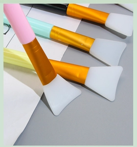 Close-up of silicone face mask brushes with colorful handles and golden metal ferrules