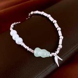 Détails d'un bracelet de perles avec billes argentées, perles blanches et un pendentif en jade