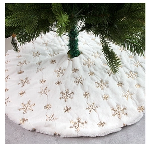 Close-up of white plush Christmas tree skirt featuring shiny golden sequin snowflake patterns