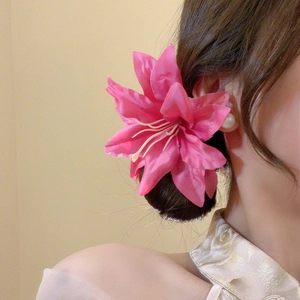 Detail of rose pink fabric lily hair clip with pearls worn on side by a model