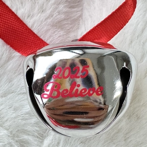 2025 Believe silver Christmas bell with red ribbon on white plush background