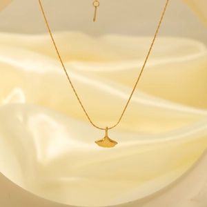 Minimalist 18k gold plated stainless steel ginkgo leaf necklace on silk background