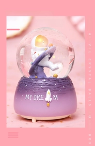 Dettaglio del carillon a sfera di cristallo astronauta con base viola e testo MY DREAM