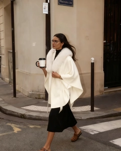 Close-up of elegant white faux fur collar and hooded shawl jacket on a city street