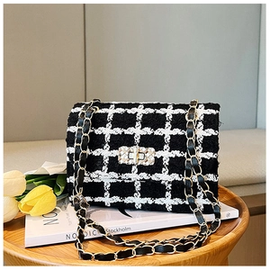 Classic black and white tweed chain bag placed on a table with decorative tulips