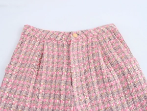 Gros plan sur la texture en tweed rose avec un bouton doré décoratif à la taille