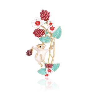 Detail shot of cute enamel squirrel brooch with red berries and heart flower on gold branch