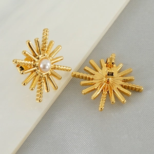 Macro shot of 18K gold starburst stud earrings with central pearl and secure backing
