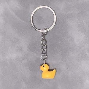 Close-up of a cute yellow resin duck pendant with a silver metal keychain and ring