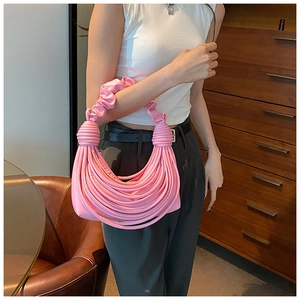Detail of creative pink pleated handbag featuring unique woven thin straps and handle design